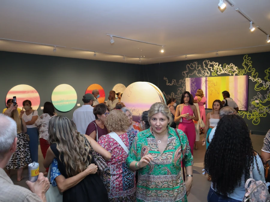 Visitor admiring Rosana Auqué’s abstract painting in violet, yellow, and green tones during the “Connection” exhibition in Santa Marta, Colombia.