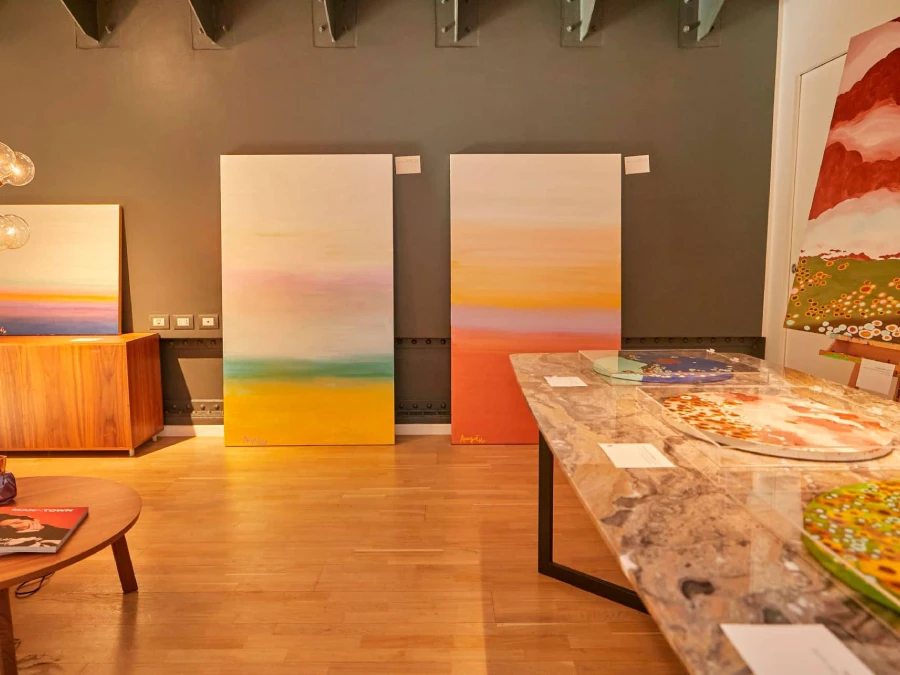 Exhibition view of Rosana Auqué’s abstract landscape paintings and circular works on marble table at FUN, Milan 2022