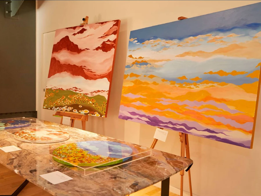 Exhibition view of FUN by Rosana Auqué at P’n’P Communication, Milan 2022, featuring colorful acrylic paintings and circular works on marble table